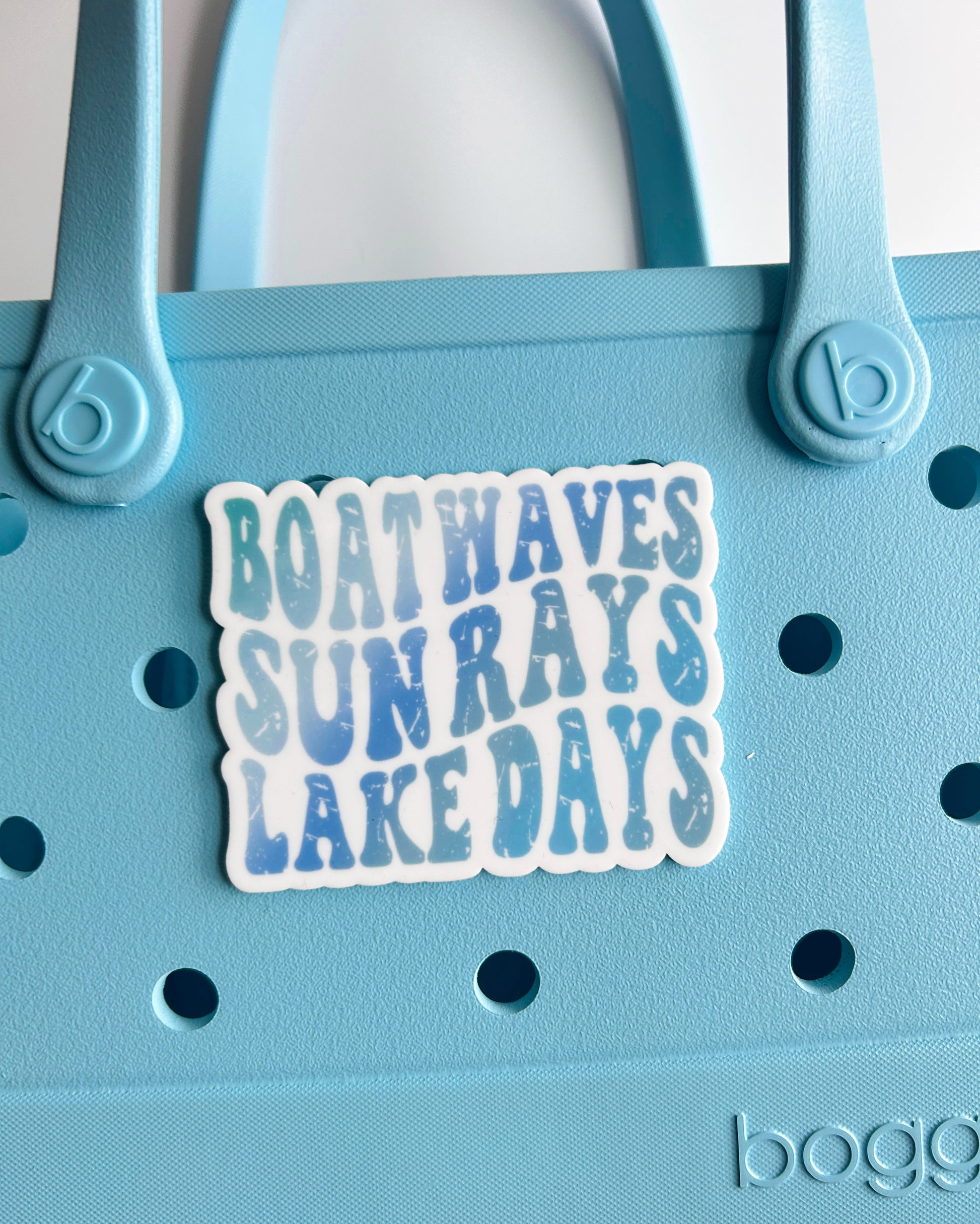 A sticker with the text "BOATWAVES SUNRAYS LAKE DAYS" is attached to a light blue plastic bag.