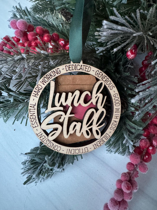A wooden ornament with the word "Lunch" carved into it, surrounded by a wreath of pine branches and red berries.