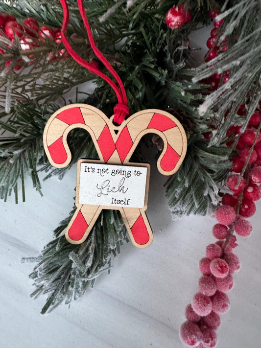 A wooden ornament shaped like a candy cane is hanging on a Christmas tree, surrounded by pine branches and red berries.