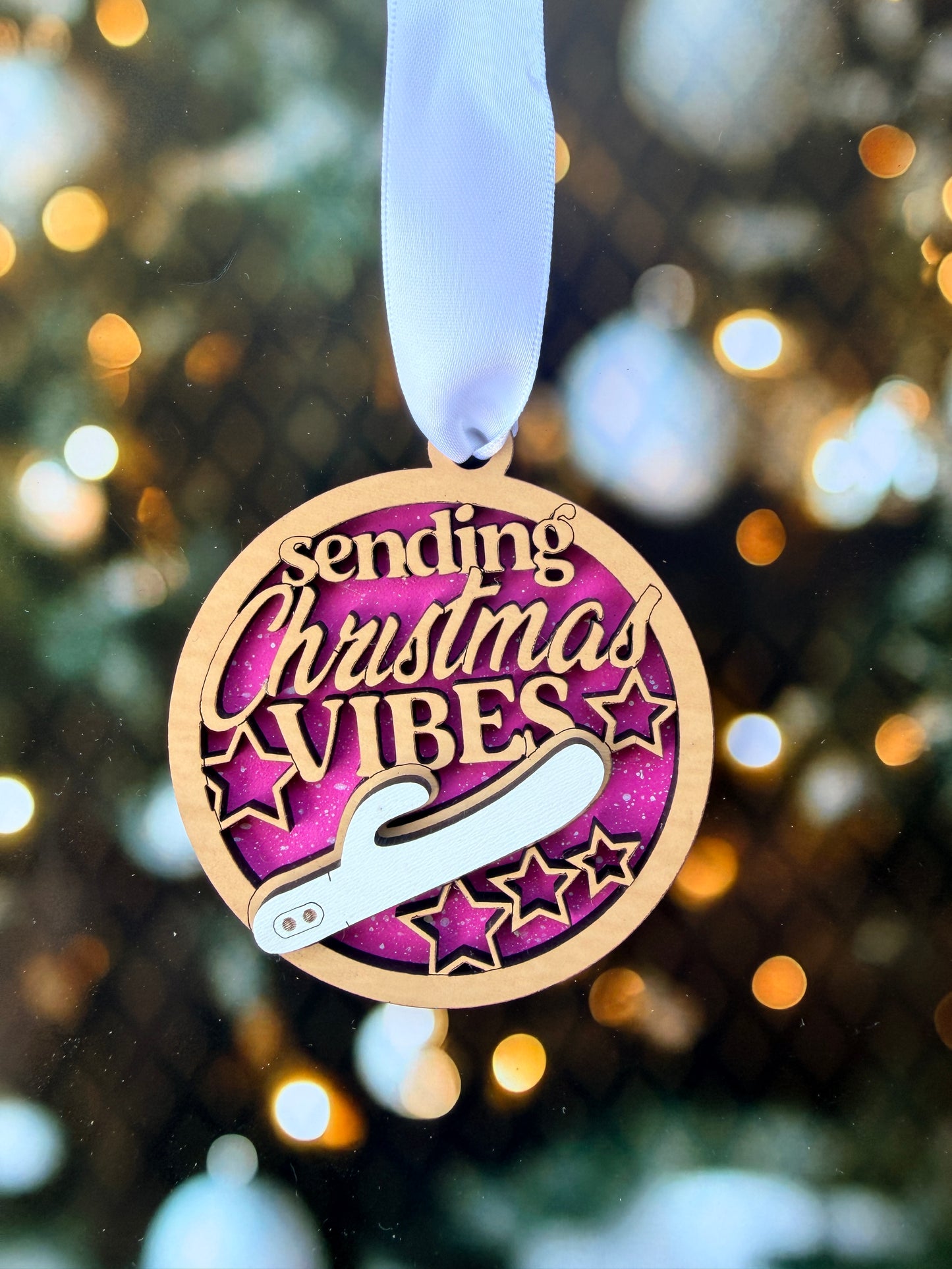 A wooden ornament with a ribbon, featuring the text "Sending Christmas vibes" and a silhouette of a figure holding a scepter.