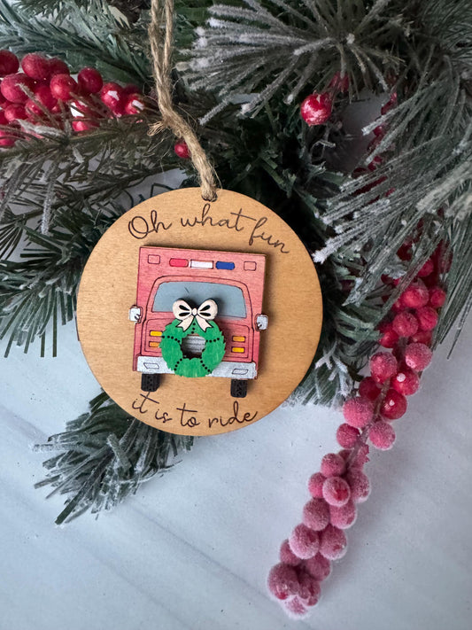 A wooden ornament with a fire truck design and the text "Oh what fun" is displayed on a Christmas tree branch, surrounded by red berries.