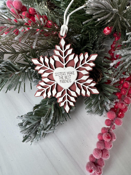A white snowflake ornament with a heart-shaped cutout in the center, surrounded by pine branches and red berries, creating a festive winter scene.