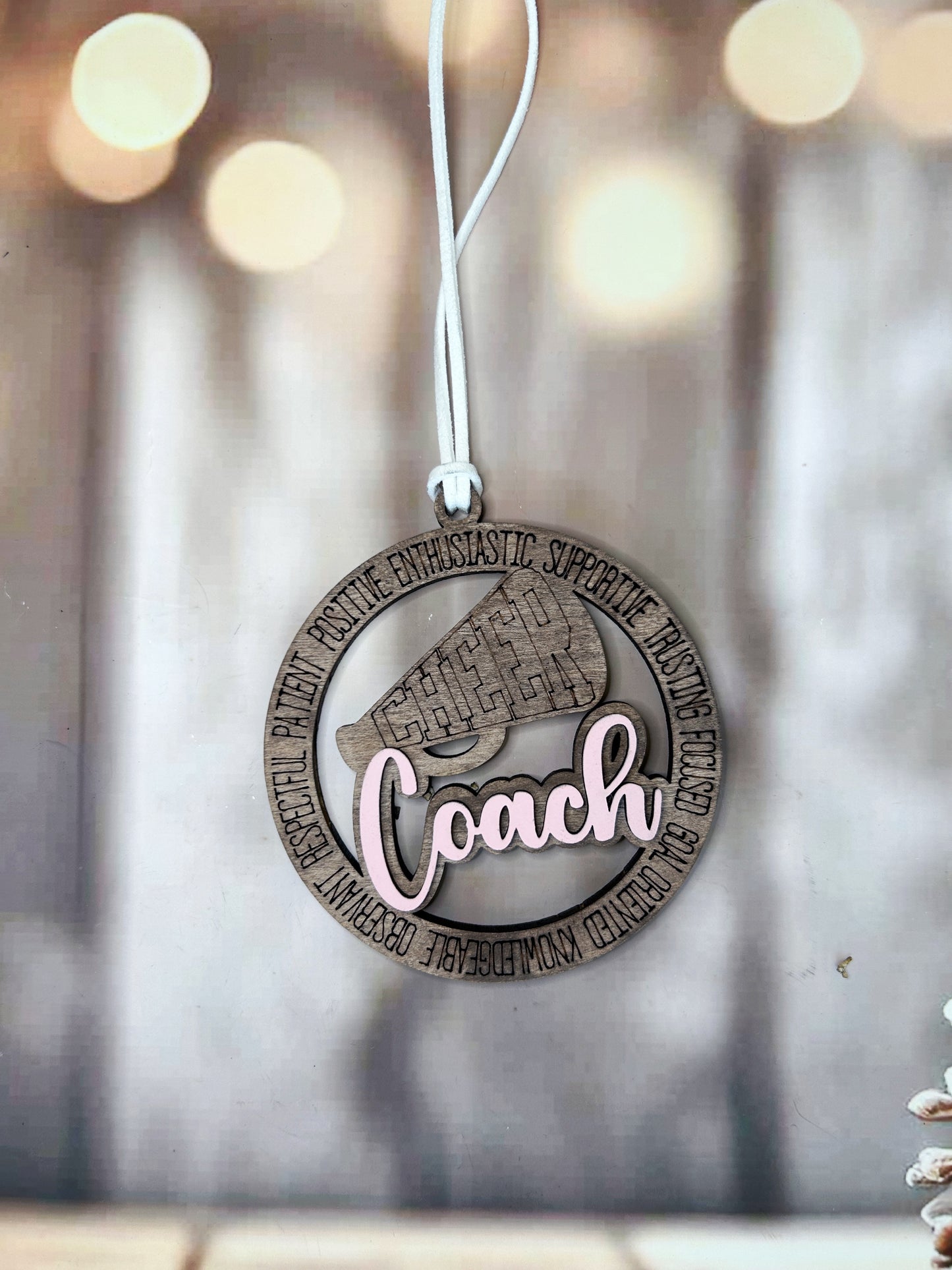 A wooden ornament with the word "Coach" written on it, hanging from a string.