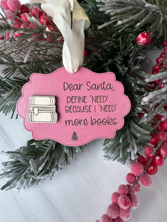 A pink ornament with a message attached to a pine branch, surrounded by red berries and greenery.