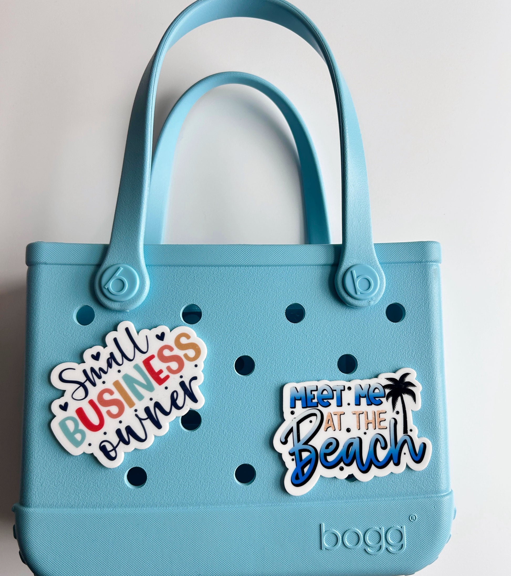 A light blue plastic tote bag with two stickers attached to it.