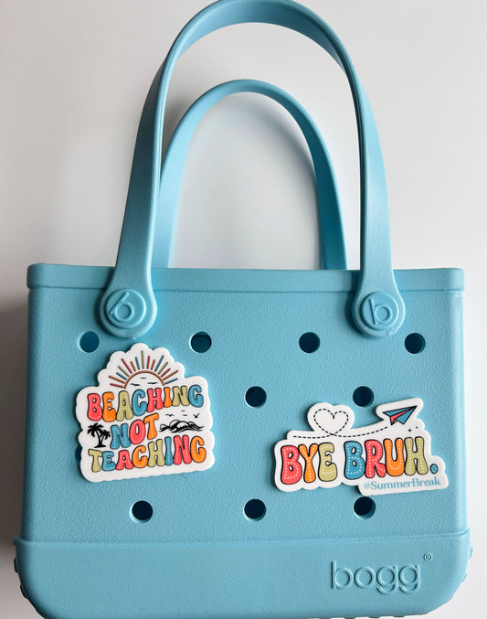 A light blue tote bag with various stickers and text on it.