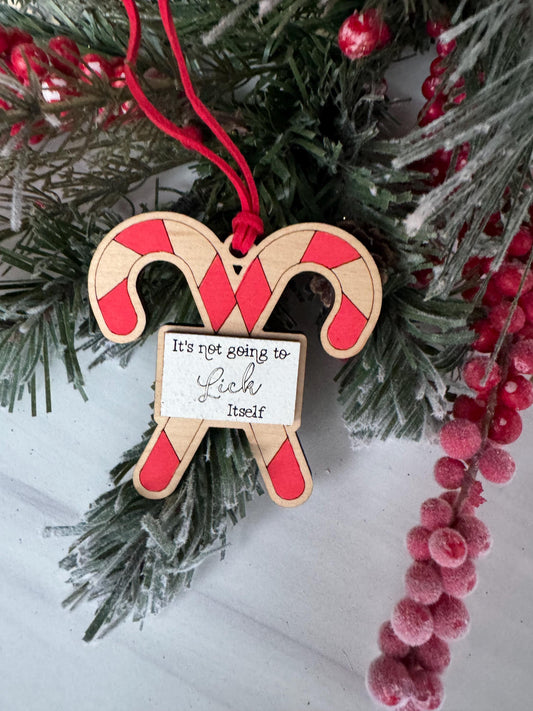 A wooden ornament shaped like a candy cane is hanging on a Christmas tree, surrounded by pine branches and red berries.