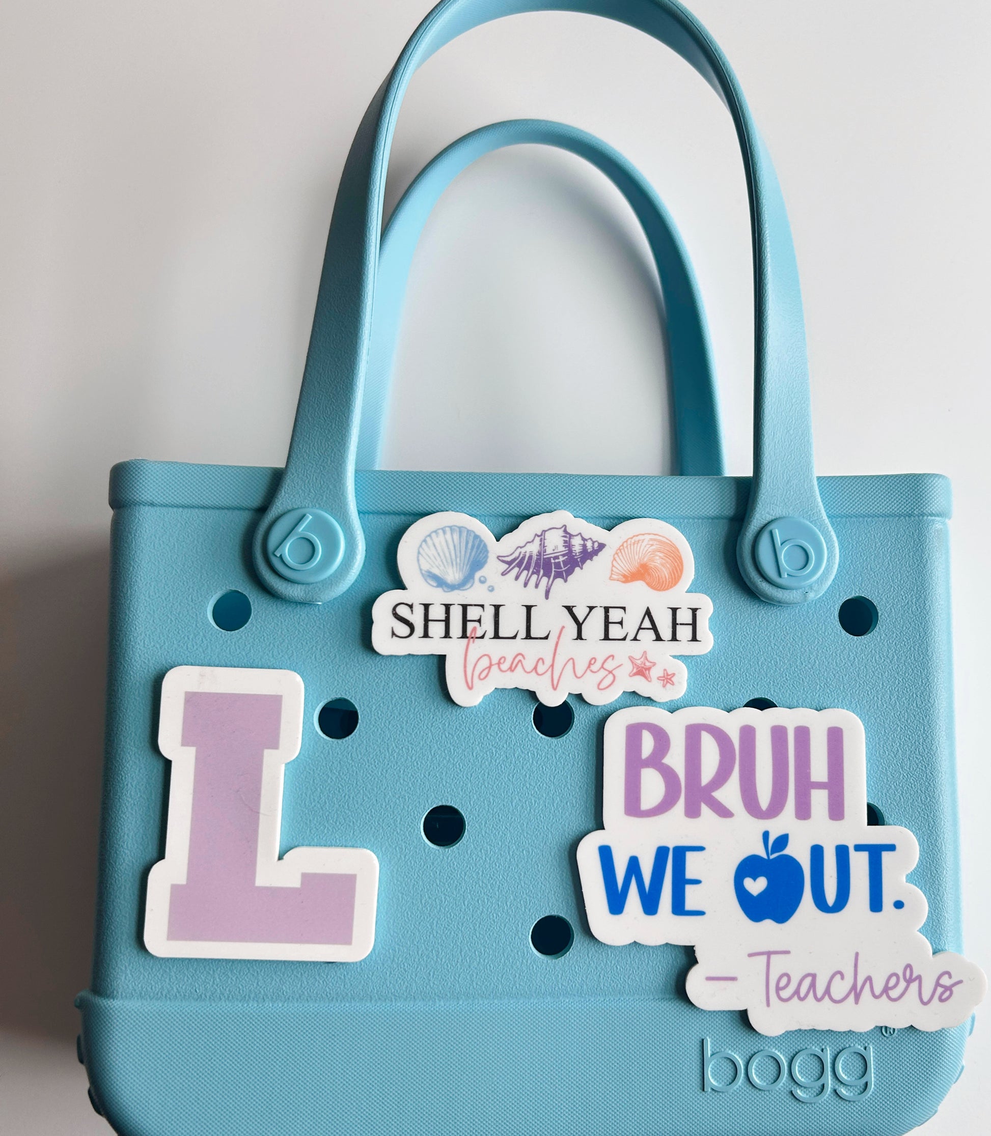 A blue plastic tote bag with various stickers and text attached to it.