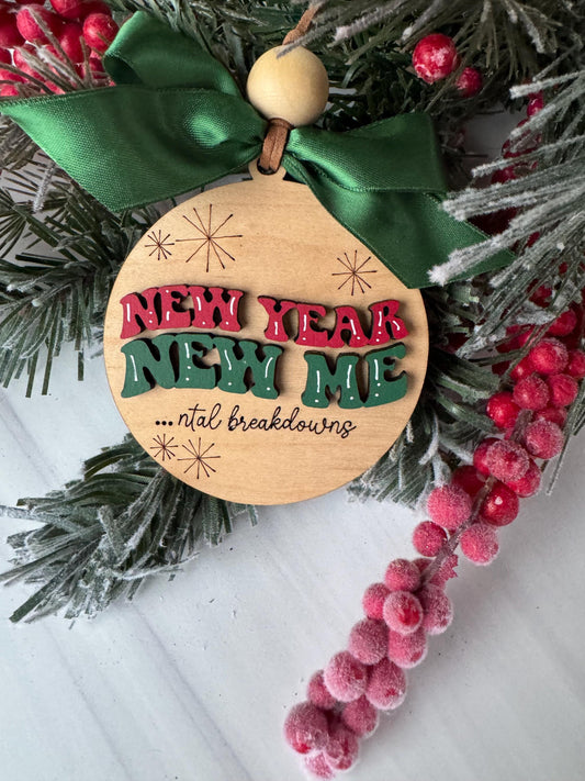 A wooden ornament with the text "Merry Christmas" and a bow is displayed among a wreath of pine branches and red berries.