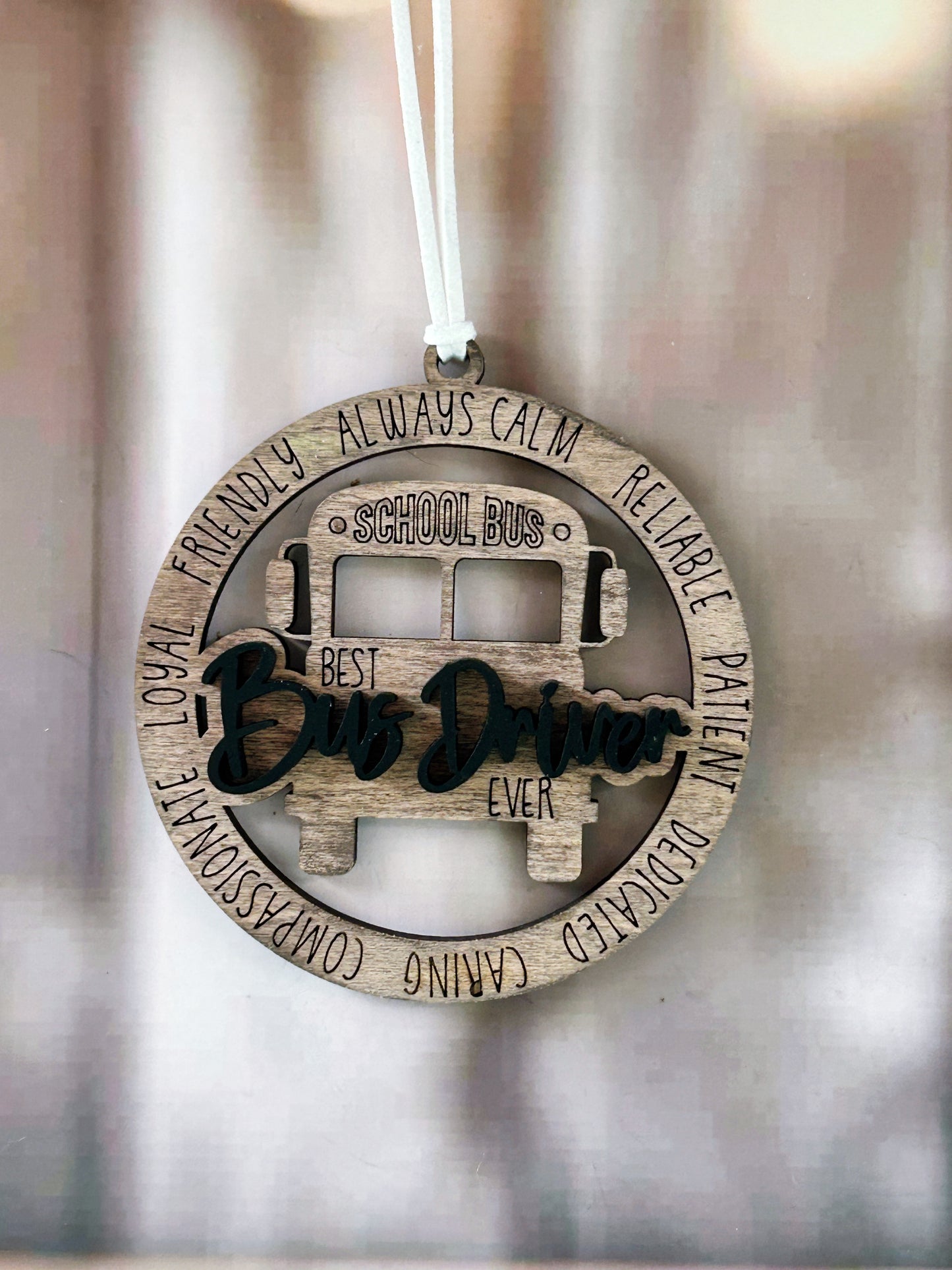 A wooden ornament shaped like a school bus, with the words "Best Bus Driver Ever" written on it.