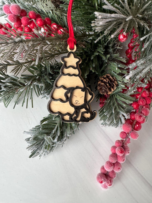 A Christmas tree ornament with a smiling face is hanging on a branch, surrounded by pine needles, red berries, and a red ribbon.