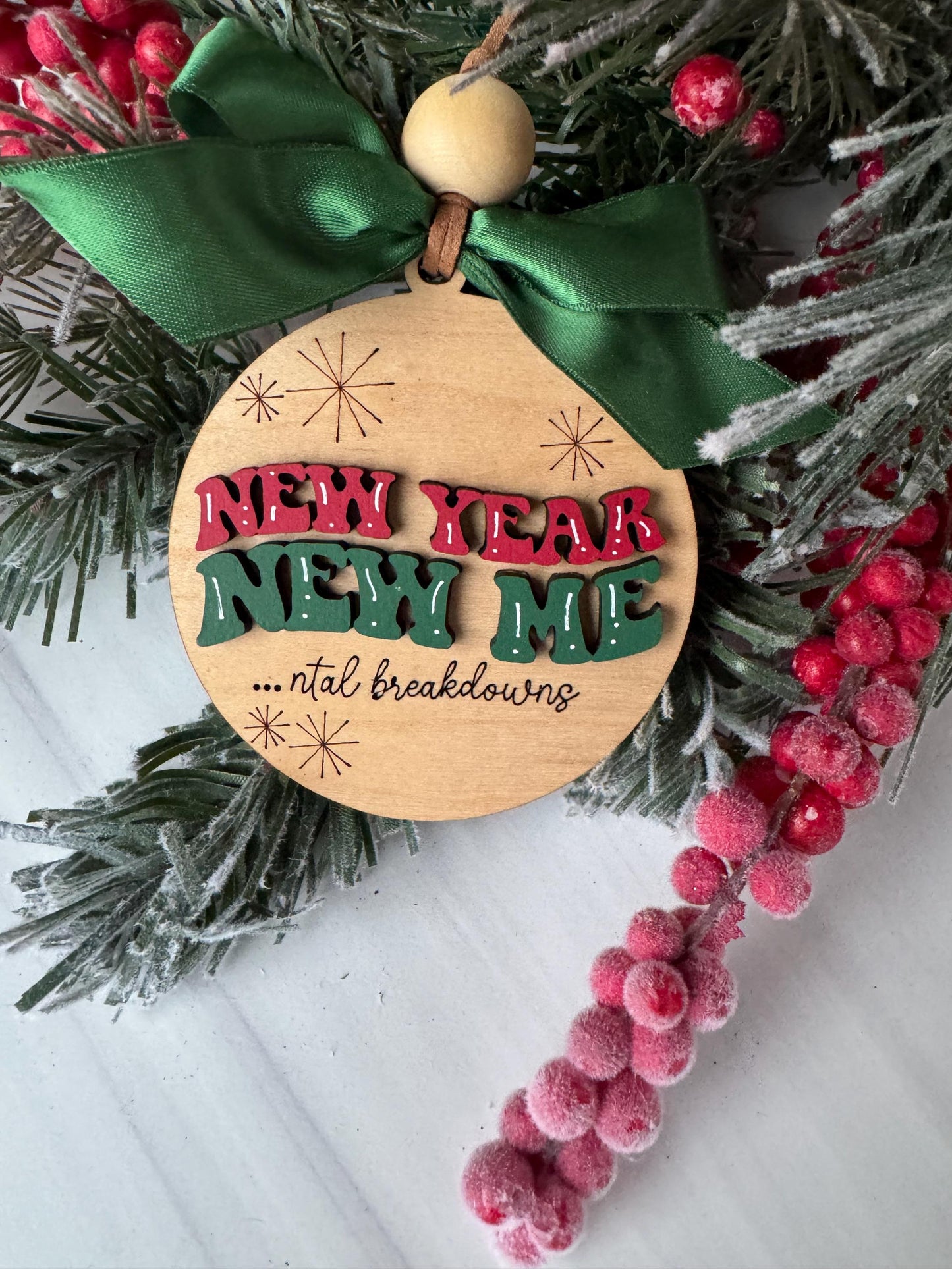 A wooden ornament with the text &quot;Merry Christmas&quot; and a bow is displayed among a wreath of pine branches and red berries.