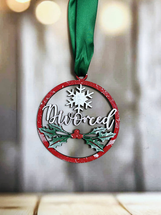A red and green ornament with the word "Divorced" written on it, hanging from a green ribbon.