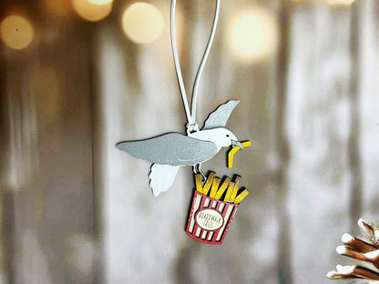 A small, colorful bird-shaped pendant with a french fry-shaped handle is displayed against a blurred background.