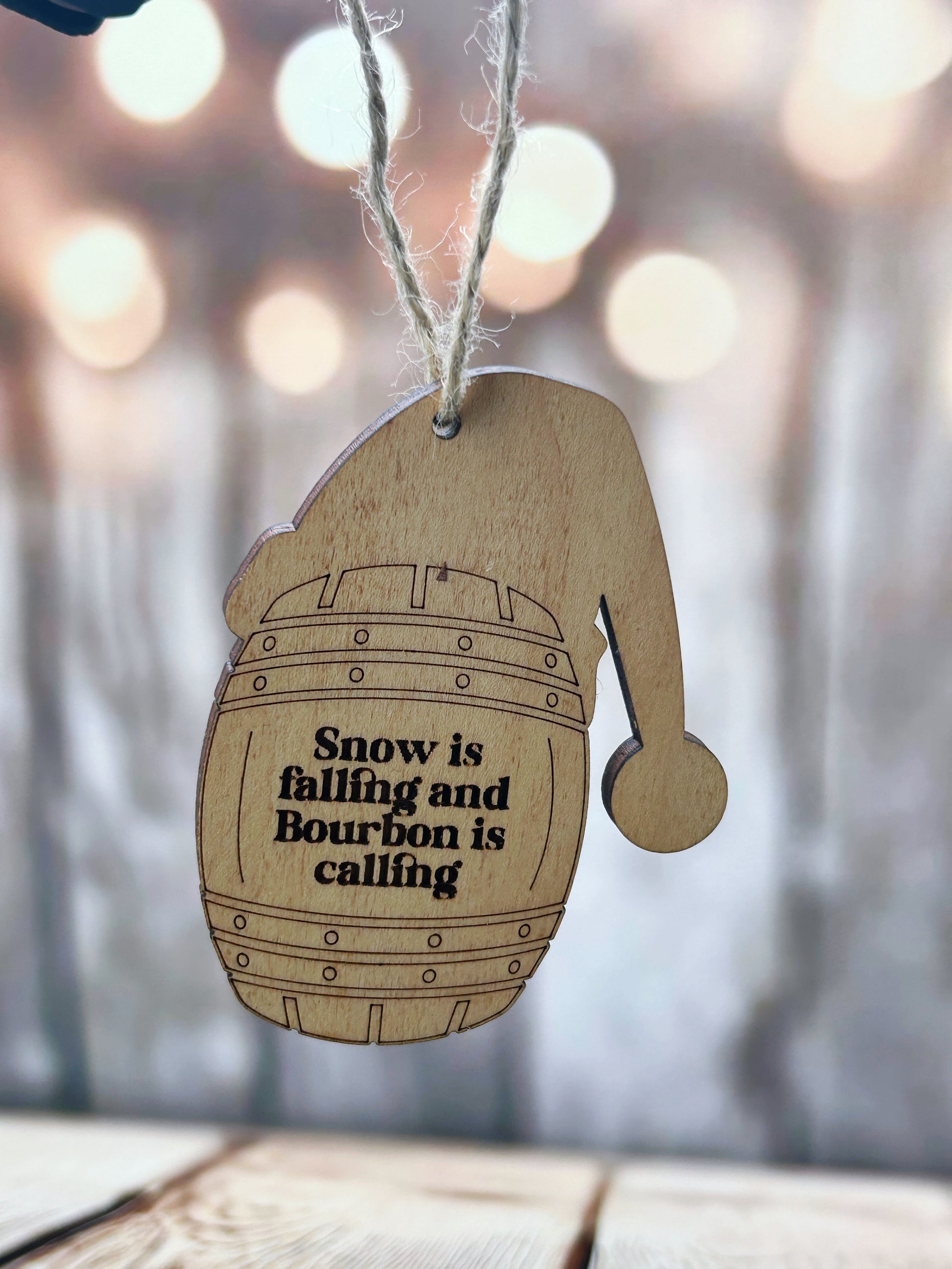 A wooden ornament with a barrel shape and a text message printed on it, hanging from a string.