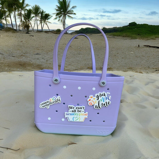 a purple handbag sitting on top of a sandy beach