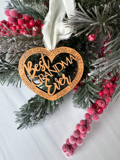 A wooden ornament with a heart shape, surrounded by pine branches, red berries, and a white ribbon.