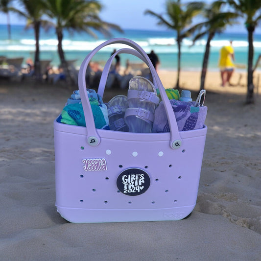 a purple bag filled with lots of items on top of a beach