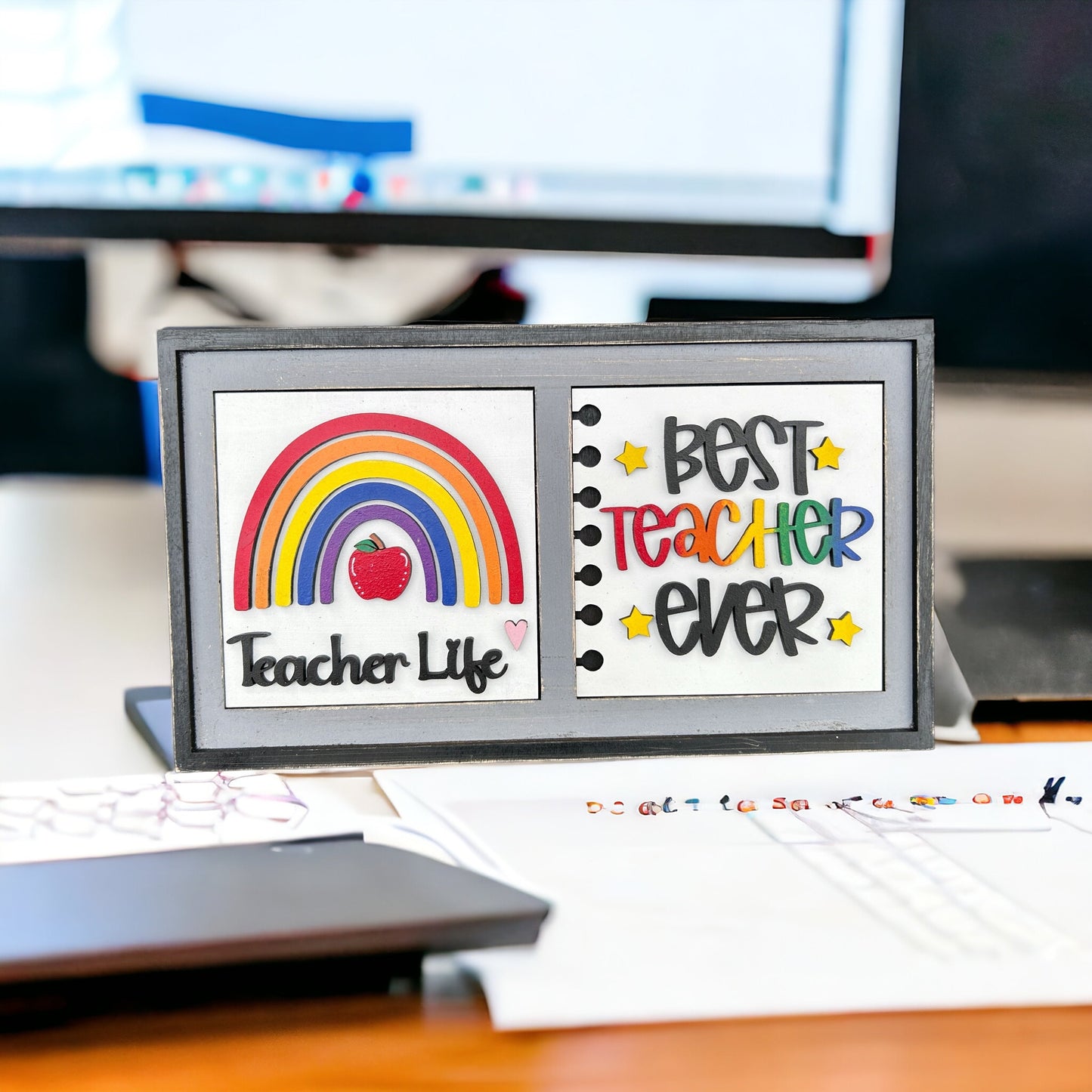 a desk with a computer monitor and a teacher's day card