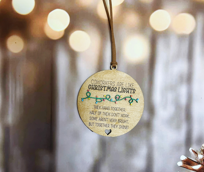 A wooden ornament with a message hangs on a wooden surface, with a blurred background of lights.
