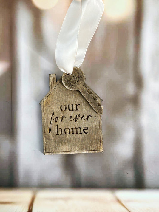 a house shaped ornament with a ribbon hanging from it