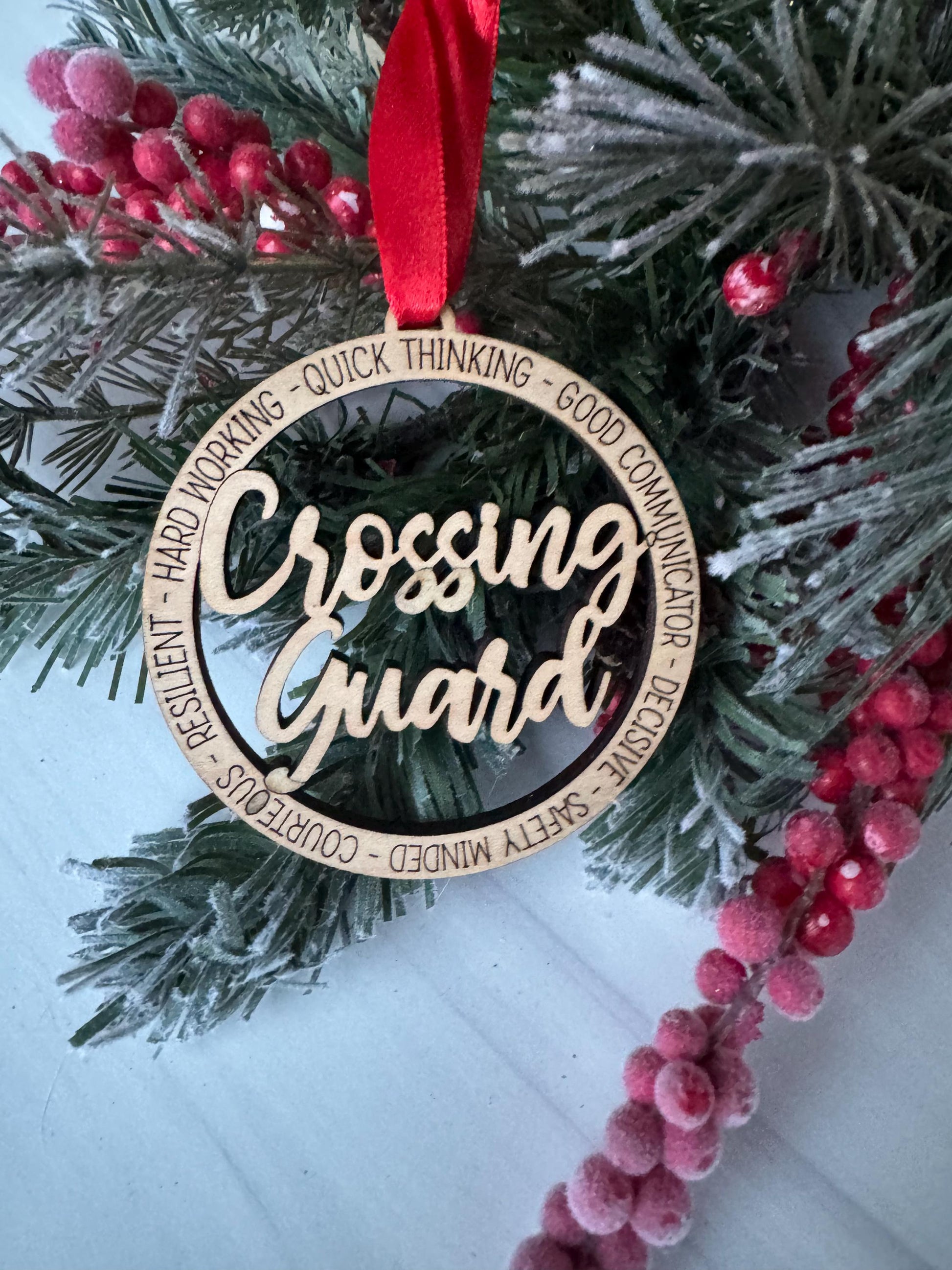 A wooden ornament with the word &quot;Gift&quot; engraved on it, surrounded by a red ribbon and placed on a pine tree branch with red berries.