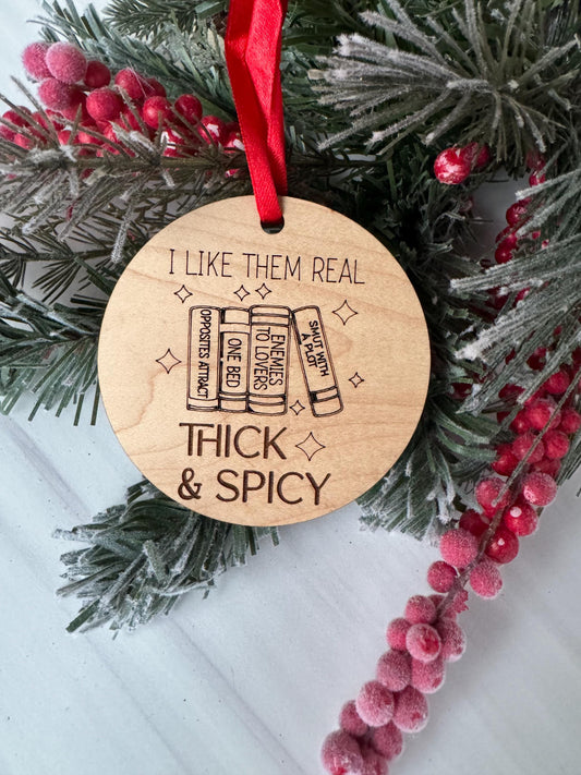 A wooden ornament with a red ribbon, featuring a humorous text and an illustration of a stack of books.