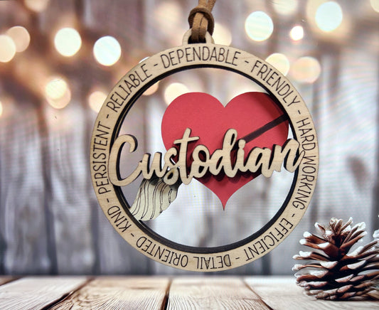 A wooden ornament with the word "Custodian" written on it, featuring a heart and a broom, is hanging on a wooden surface.
