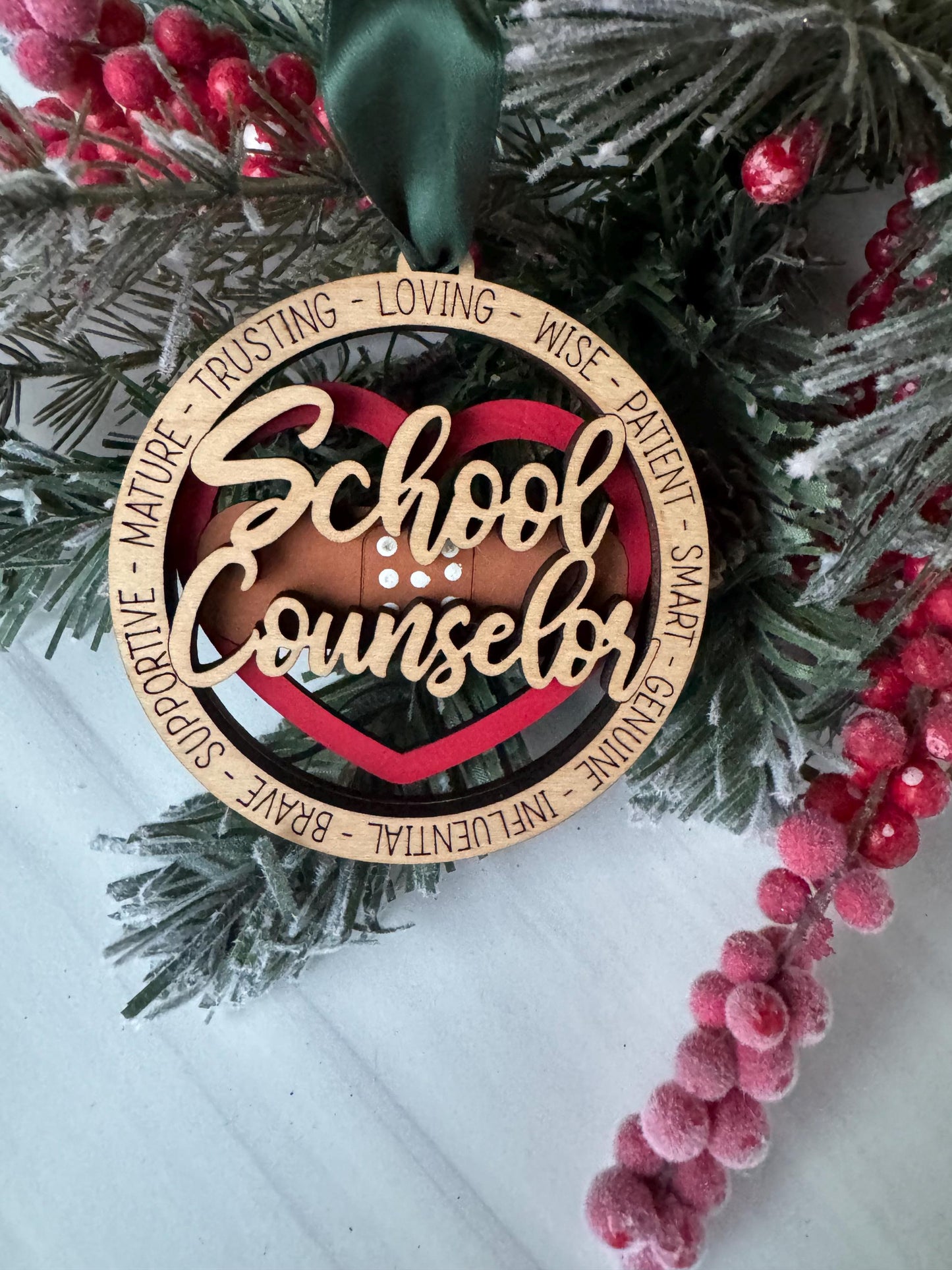 A wooden ornament with the word &quot;School Counselor&quot; written on it, surrounded by a wreath of pine branches and red berries.
