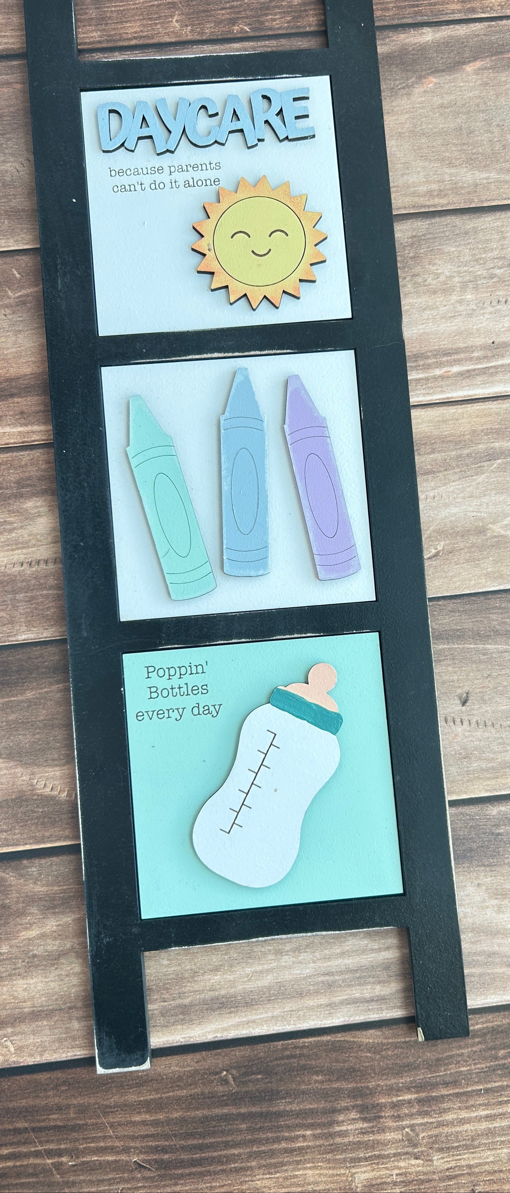 Three cards with illustrations of a bottle, crayons, and a sun on a wooden surface.