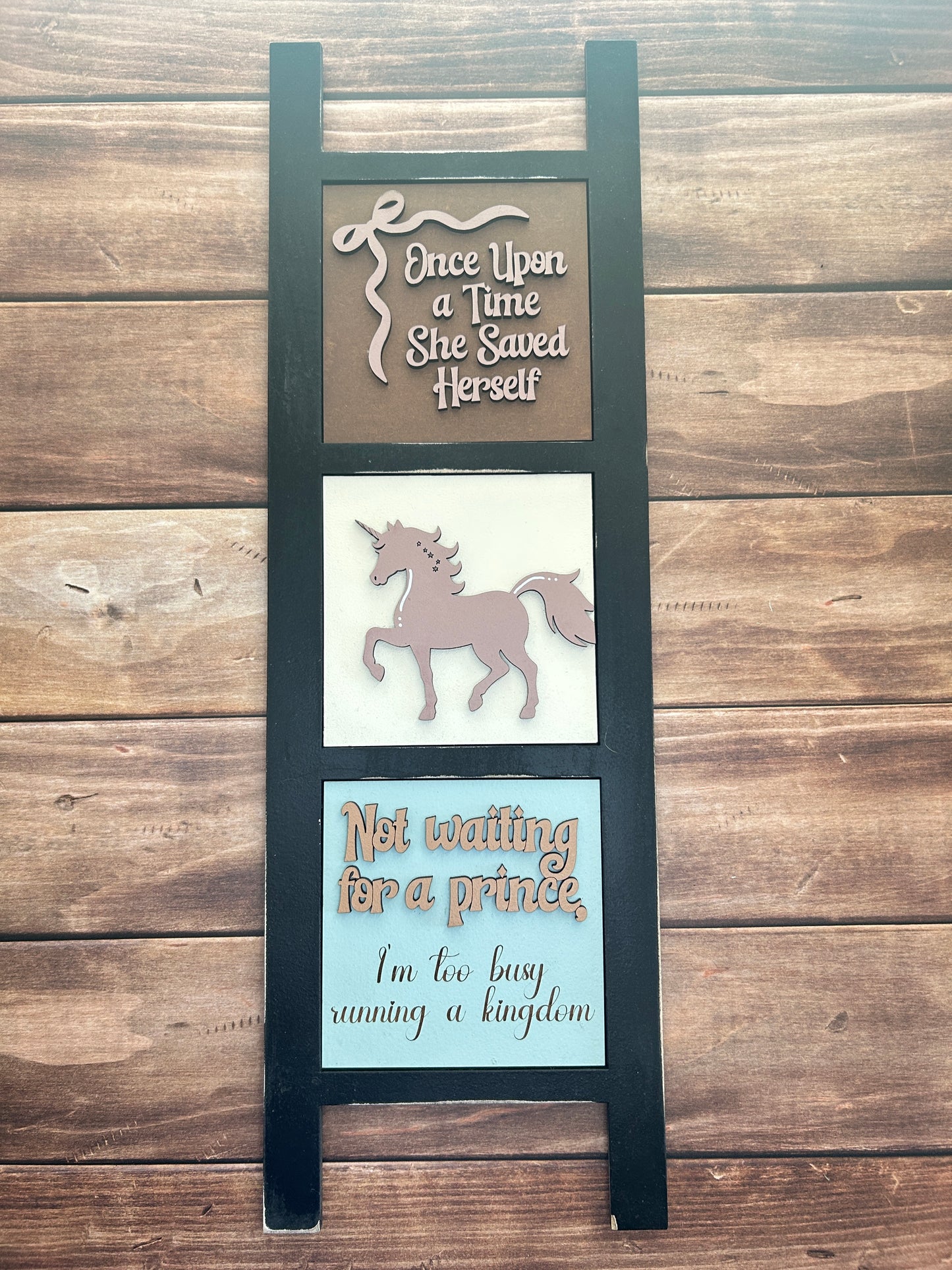 Decorative sign with unicorn design and text on a wooden background