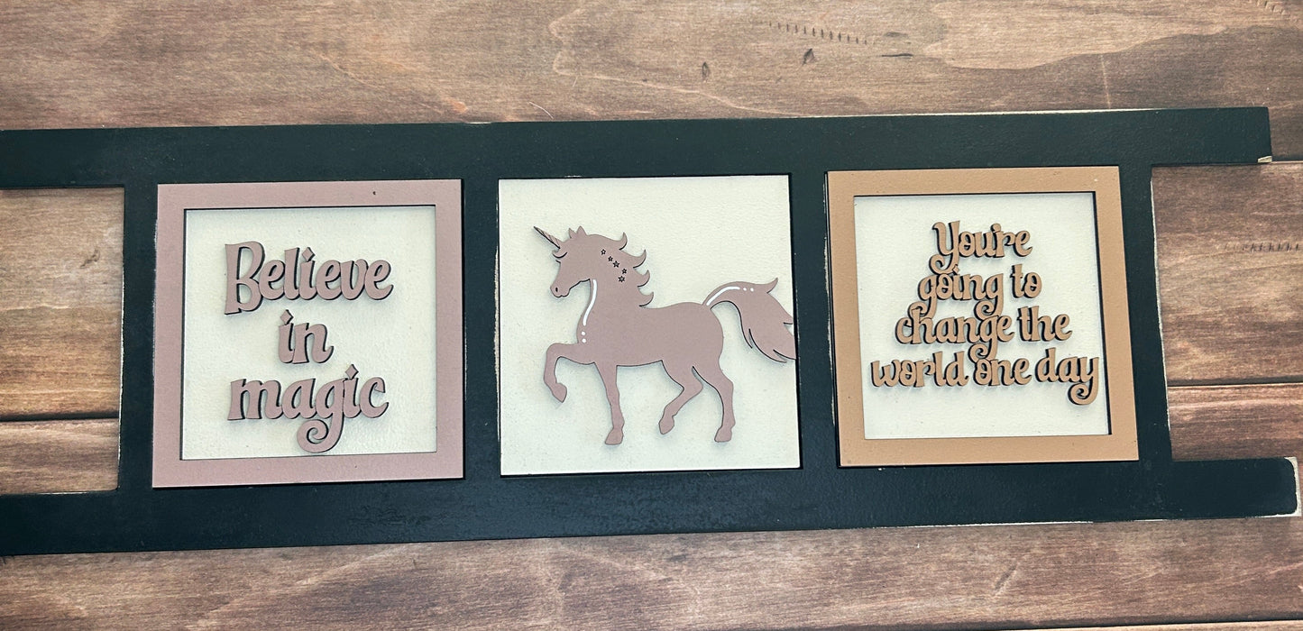 Decorative wall art with framed quotes and a unicorn silhouette on a wooden background