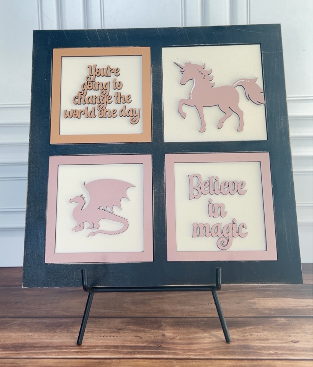 Decorative wall art with unicorn, dragon, and motivational phrases on a black frame.