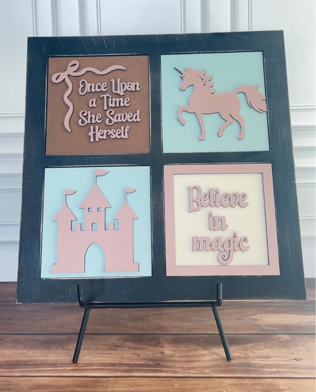 Decorative wall art with fairy tale elements on a stand against a white wall.