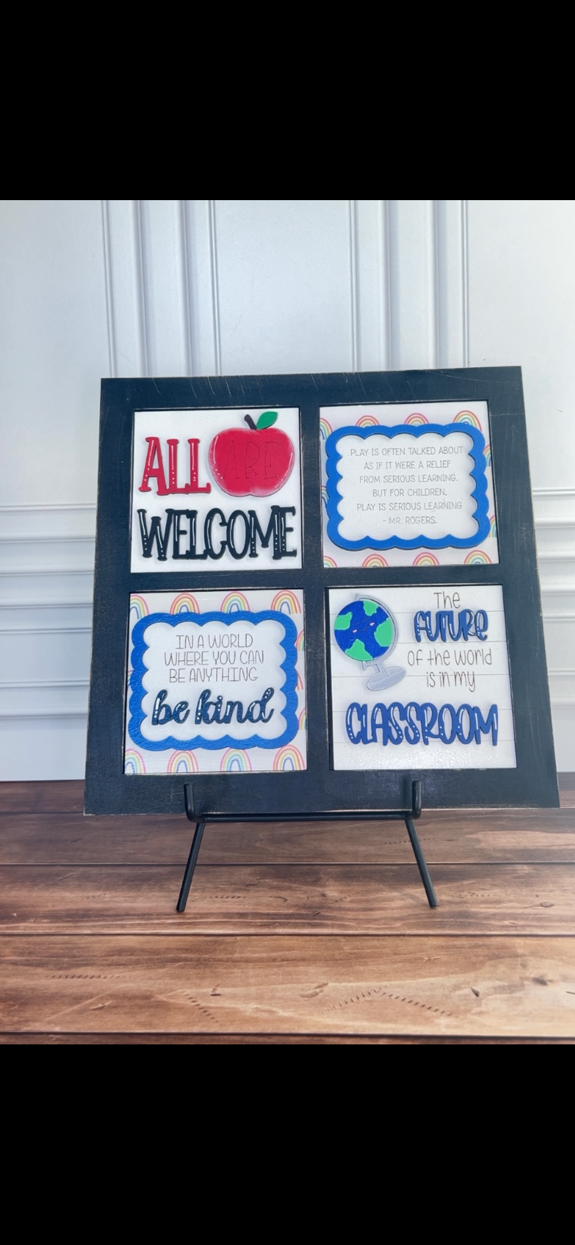 Decorative sign with educational-themed text and graphics on a stand against a white wall.