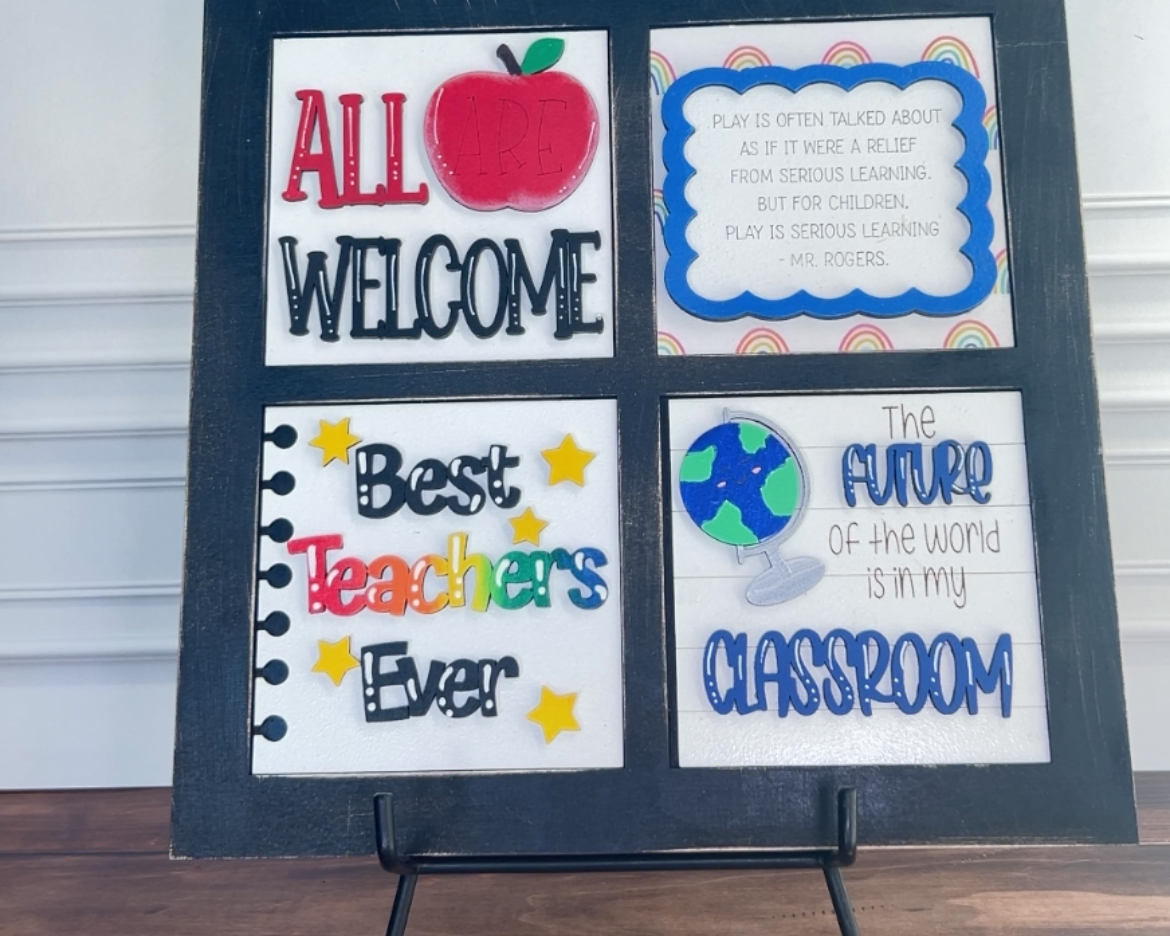 Decorative sign with colorful text and graphics on a stand against a white wall.