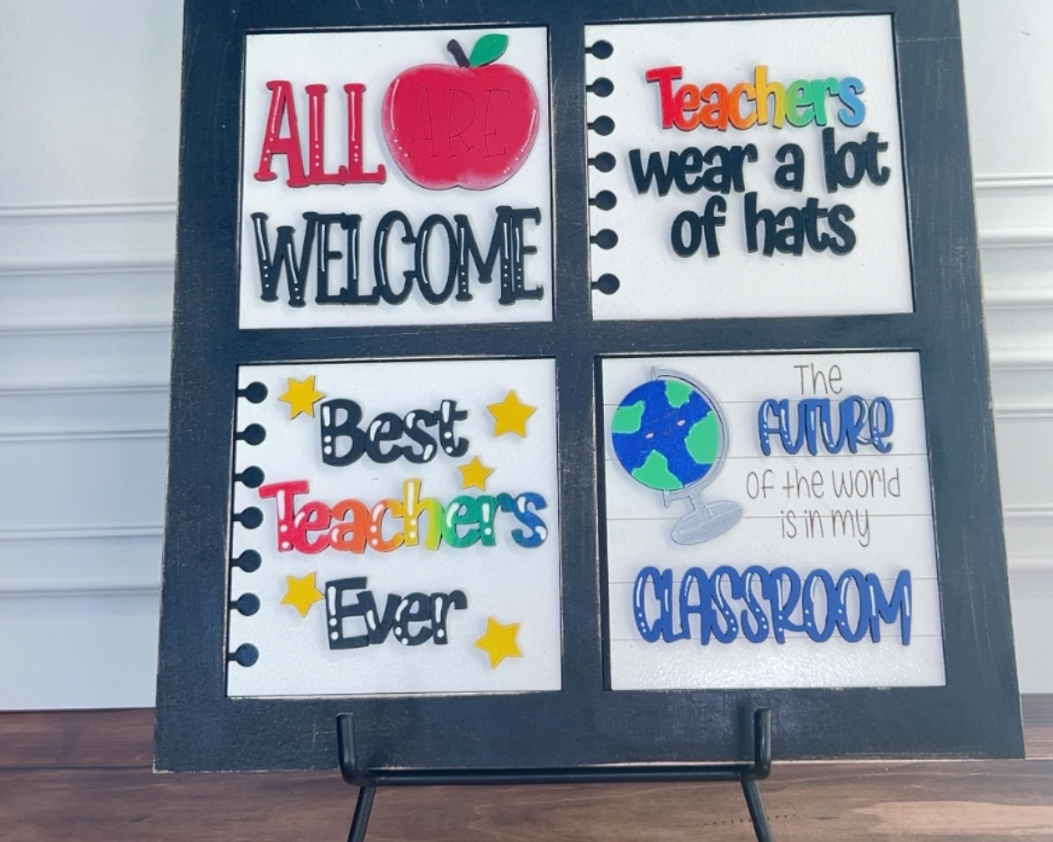 Decorative sign with text and graphics on a stand against a white wall.