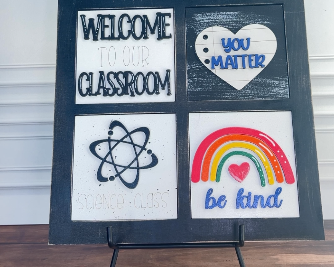 Decorative sign with motivational phrases on a stand against a white wall.