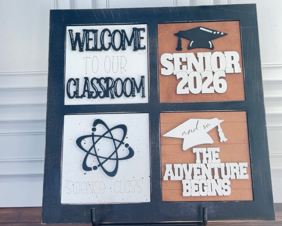 Decorative sign with text and graphics on a stand against a white wall.