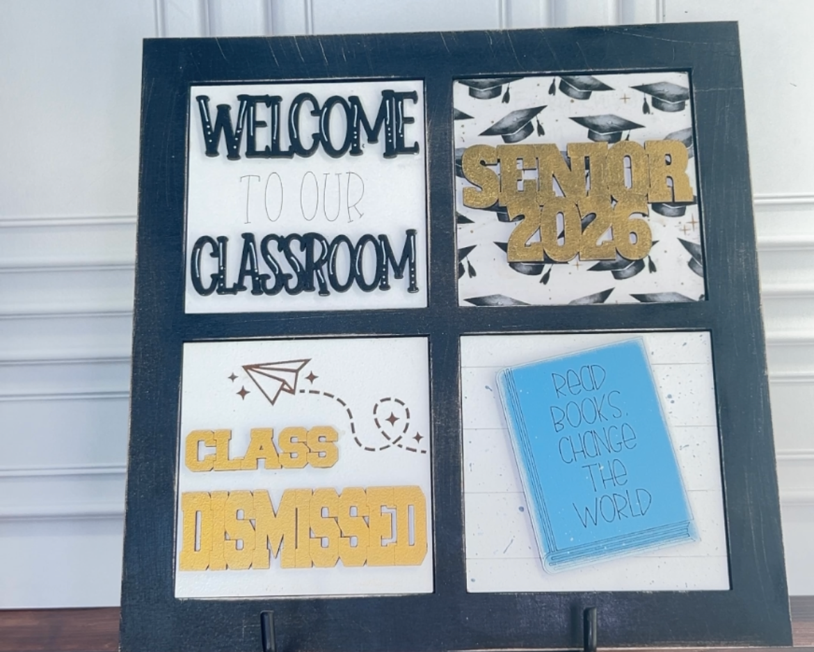 Decorative sign with text and graphics on a stand against a white wall.