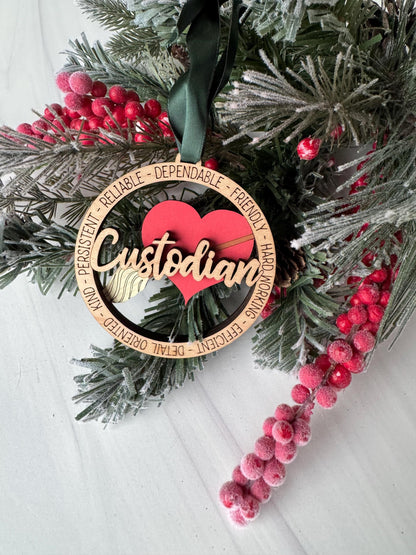 A Christmas ornament with the word "Custodian" on it, surrounded by pine branches, red berries, and a green ribbon.