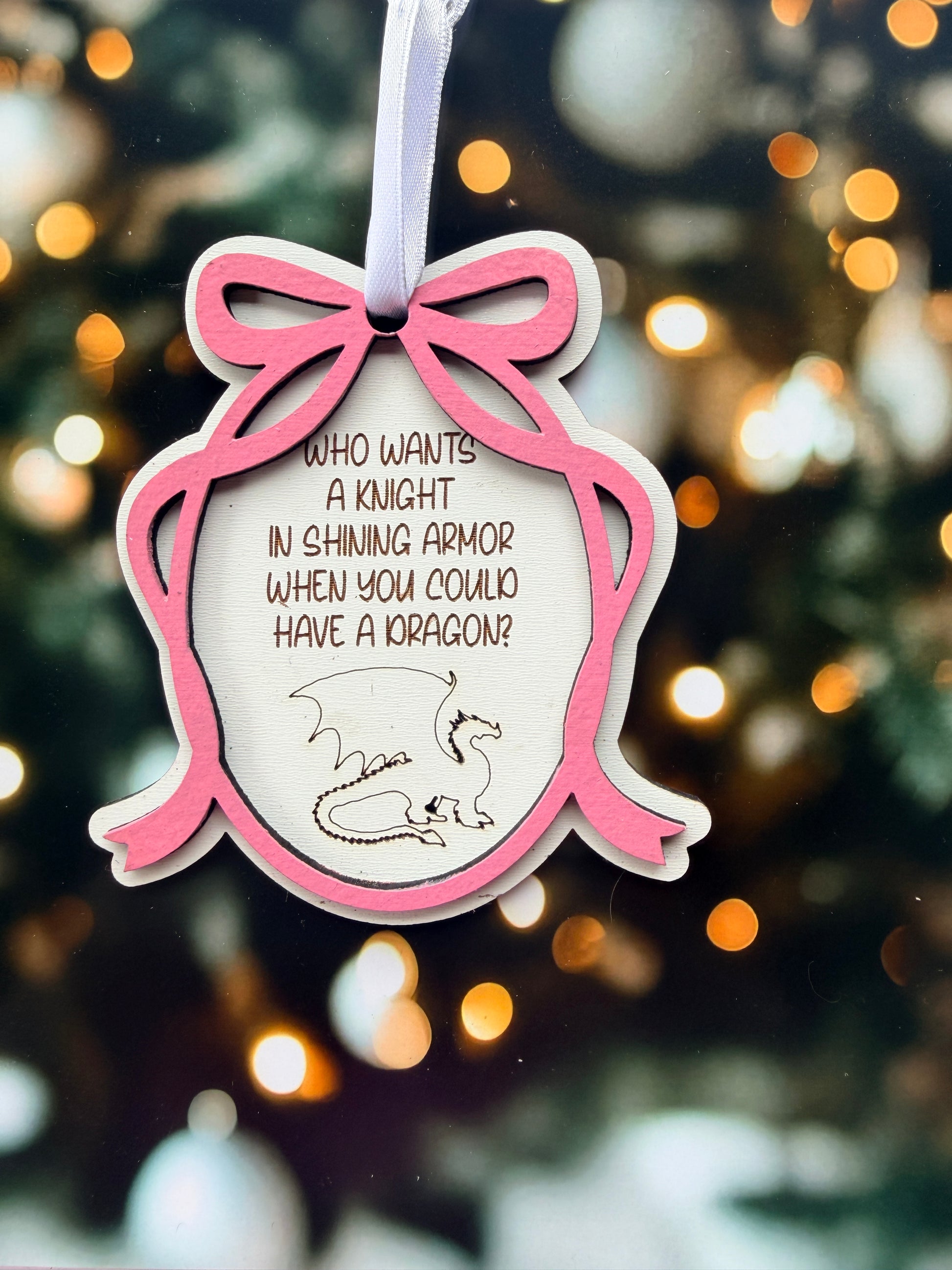 A pink wooden ornament with a dragon design, featuring a text that reads "Who wants a knight in shining armor when you could have a dragon?".