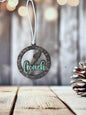 A circular ornament with the word "Coach" written on it, hanging from a string against a blurred background.