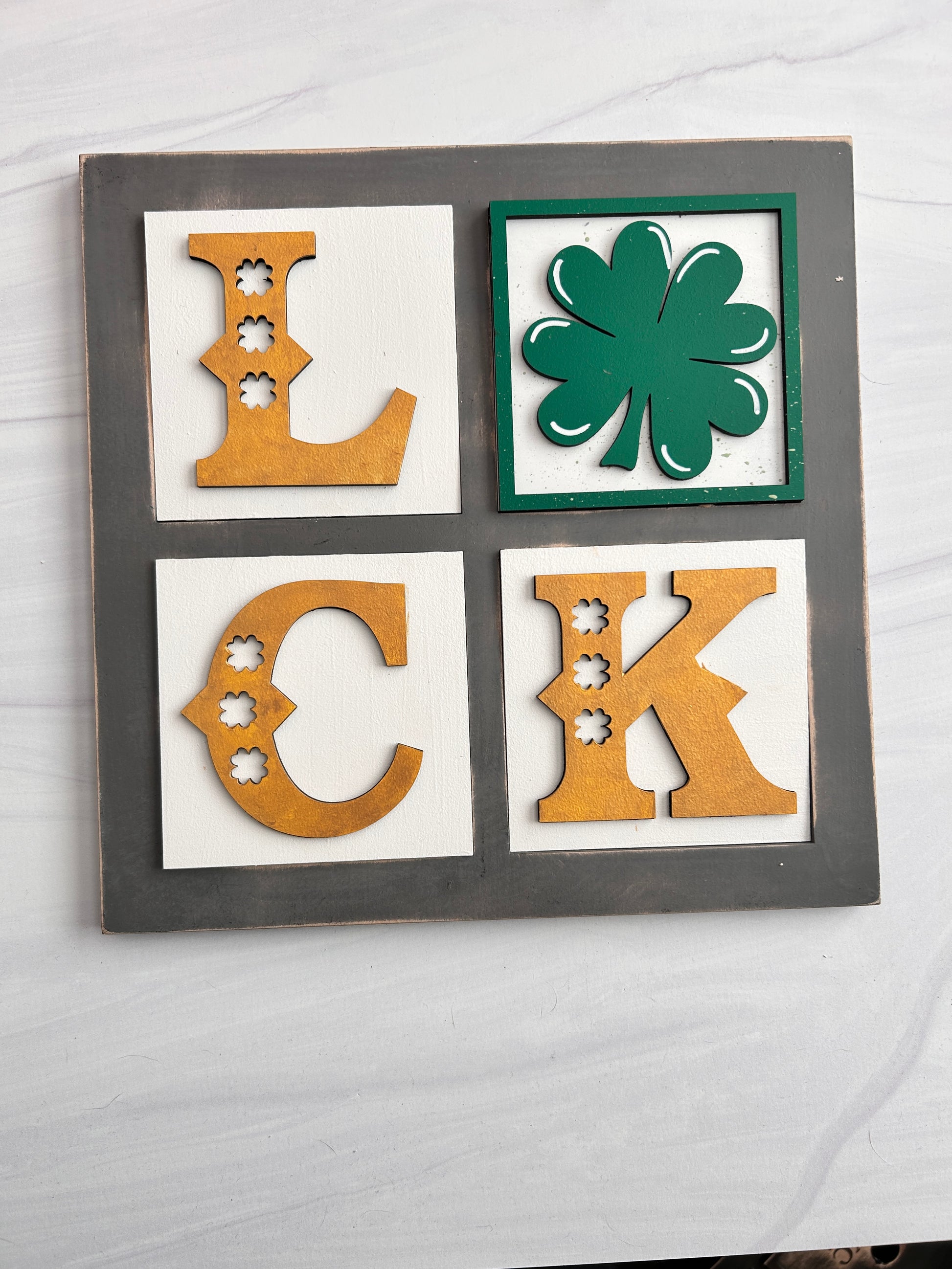 four distinct symbols, including a green shamrock, a skull, a crescent moon, and a horseshoe, arranged in a square frame.