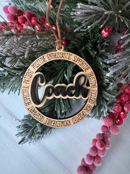 A wooden ornament with the word &quot;JOY&quot; carved into it, surrounded by a wreath of pine branches and red berries.