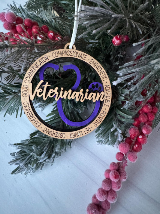 A Christmas ornament with the word "Veterinarian" written on it, surrounded by pine branches and red berries.