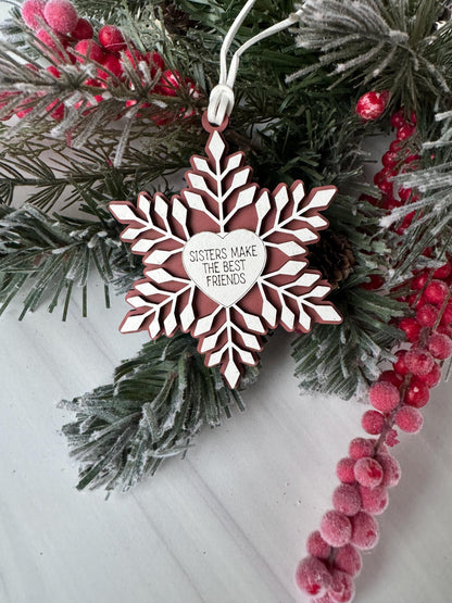A white snowflake ornament with a heart-shaped cutout in the center, surrounded by pine branches and red berries, creating a festive winter scene.