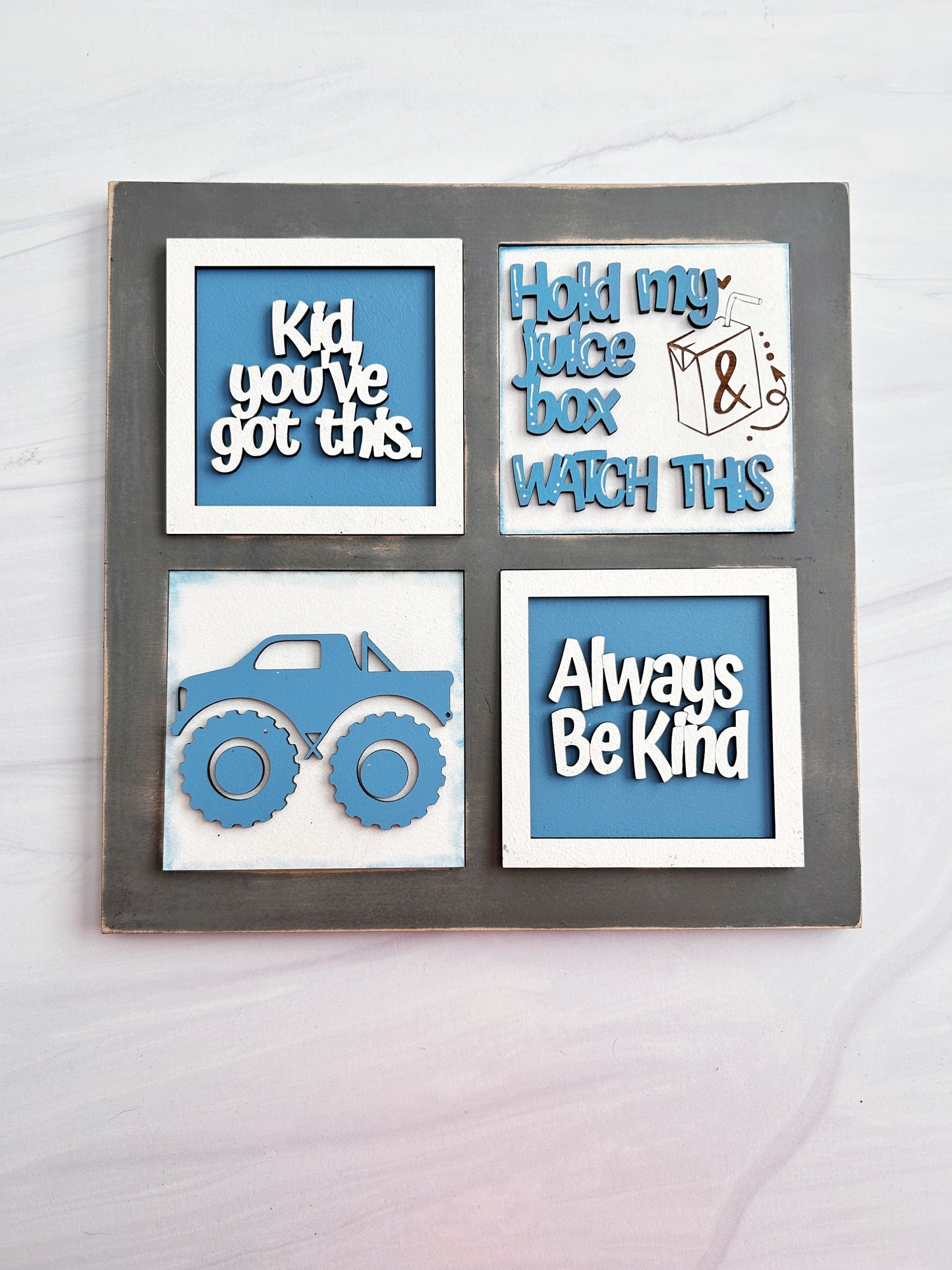 The image is a collage of four framed pieces, each containing a different message or illustration. The first piece says "Kid you've got this," the second piece says "Hold my juice box watch this," the third piece says "Always Be Kind," and the fourth piece says "The image depicts a monster truck."
