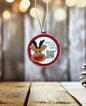 A Christmas ornament with a reindeer and the text "Scan to track Santa" is hanging on a string against a blurred background with bokeh lights.