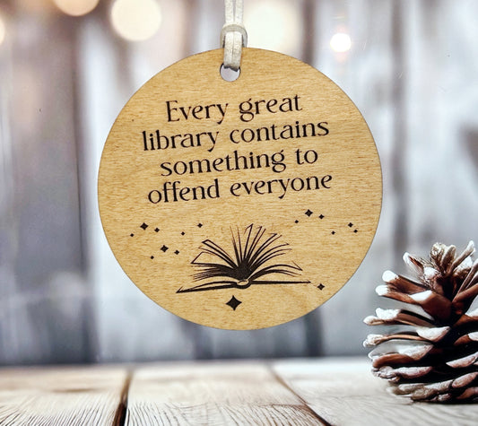 A wooden ornament with a quote about libraries and books, hanging on a string.